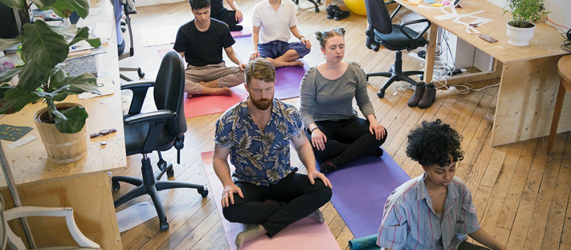 Serene creative business people meditating in office.